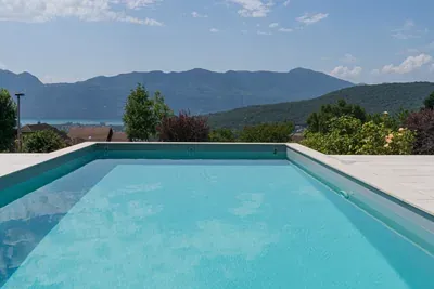 Bassin turquoise aux margelles claires devant les montagnes, à Grésy-sur-Aix