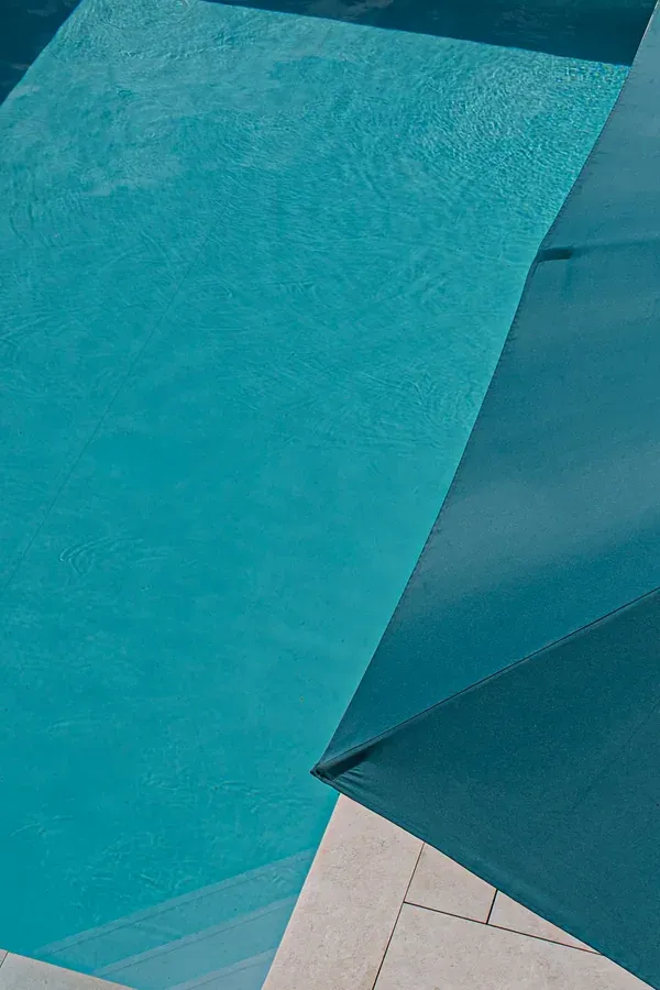 Volet de piscine turquoise déroulé sur un bassin, vu de dessus