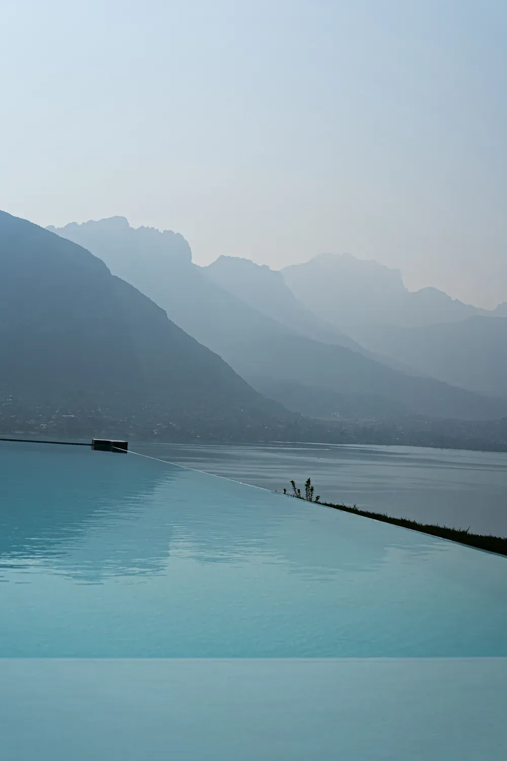 Piscine à débordement face au lac d’Annecy et aux montagnes dans la brume
