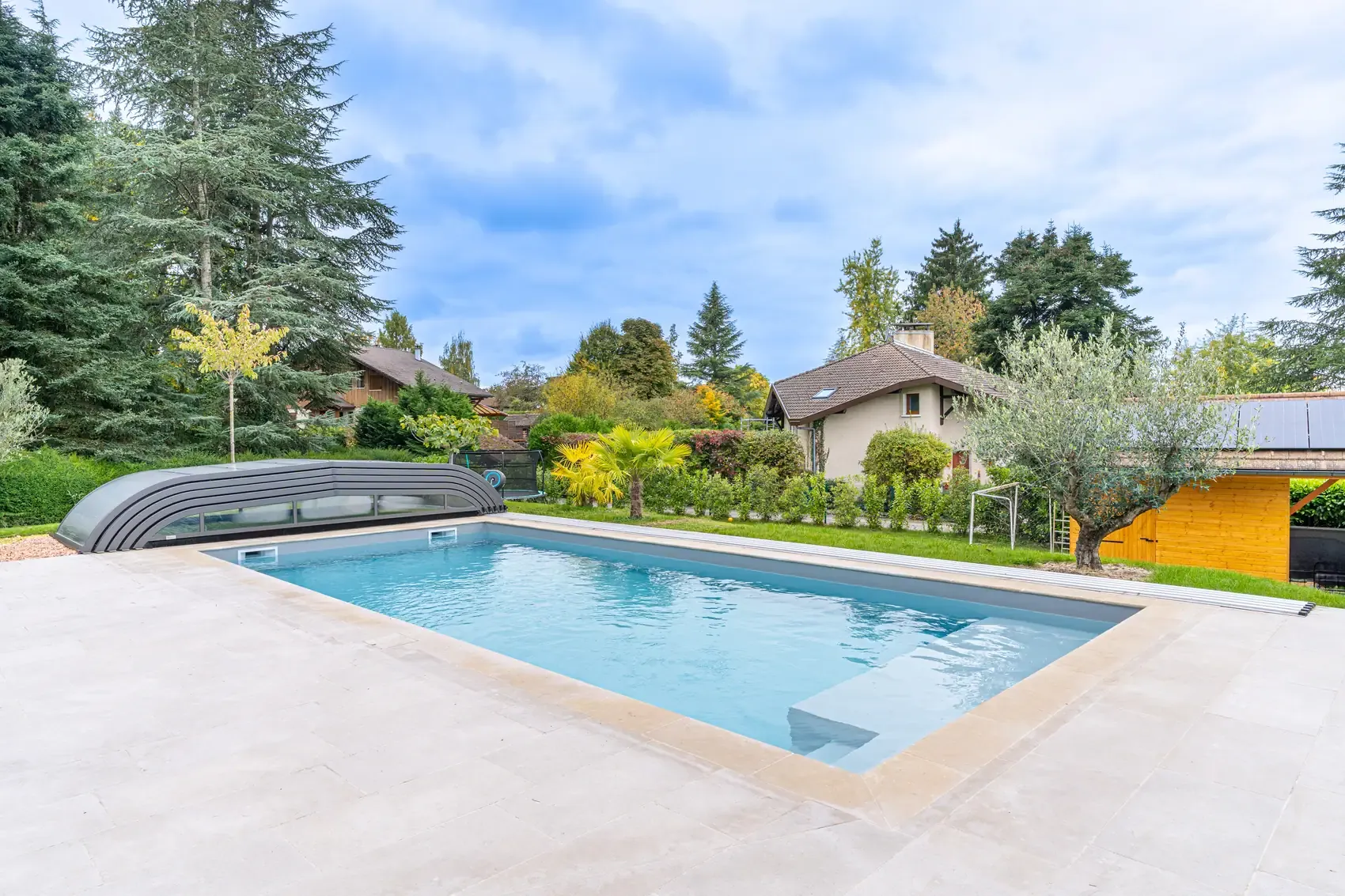 Piscine sur mesure avec plage immergée et margelles claires à Quintal