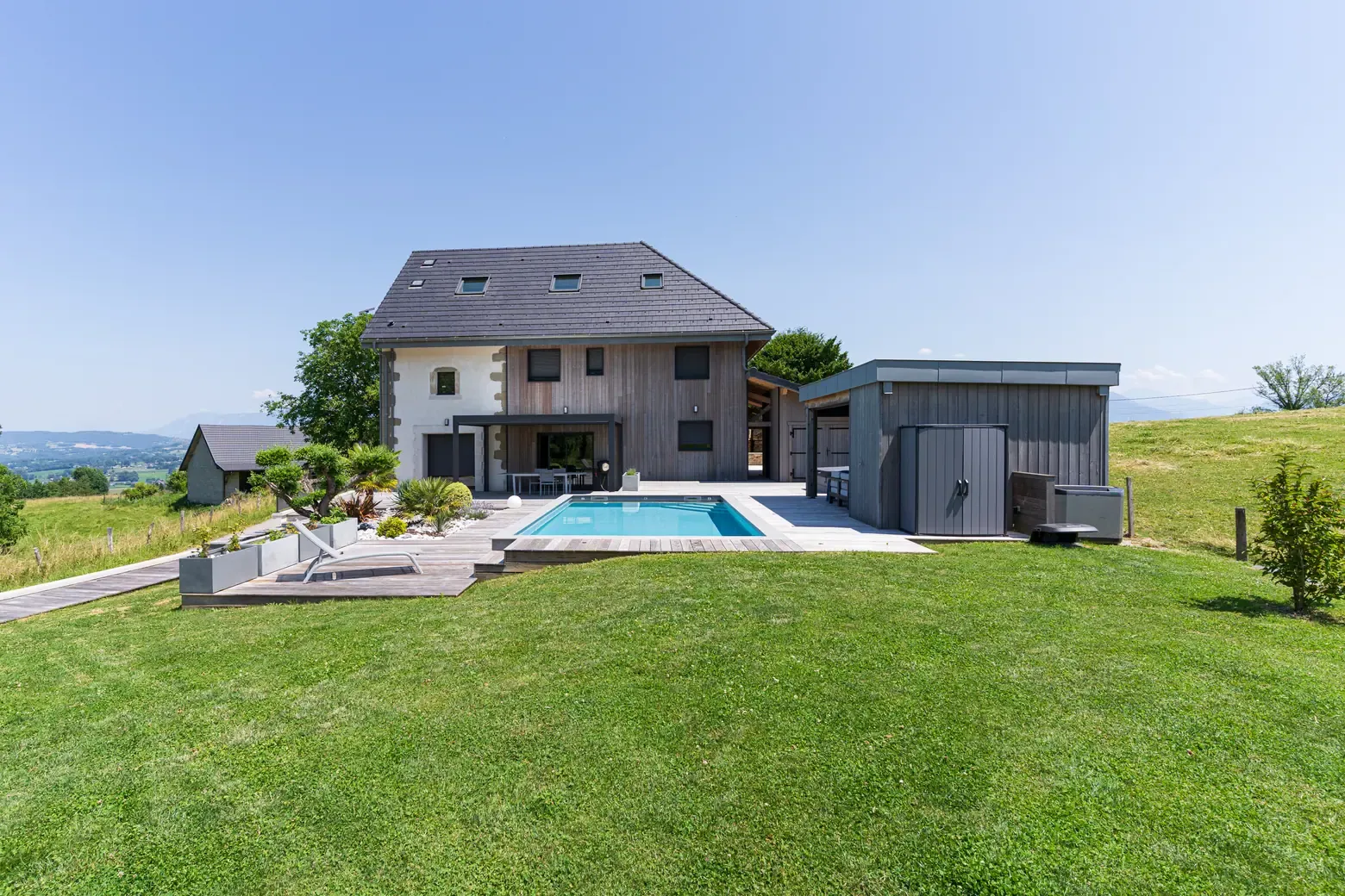 Piscine avec volet immergé et plage en pierre à Rumilly